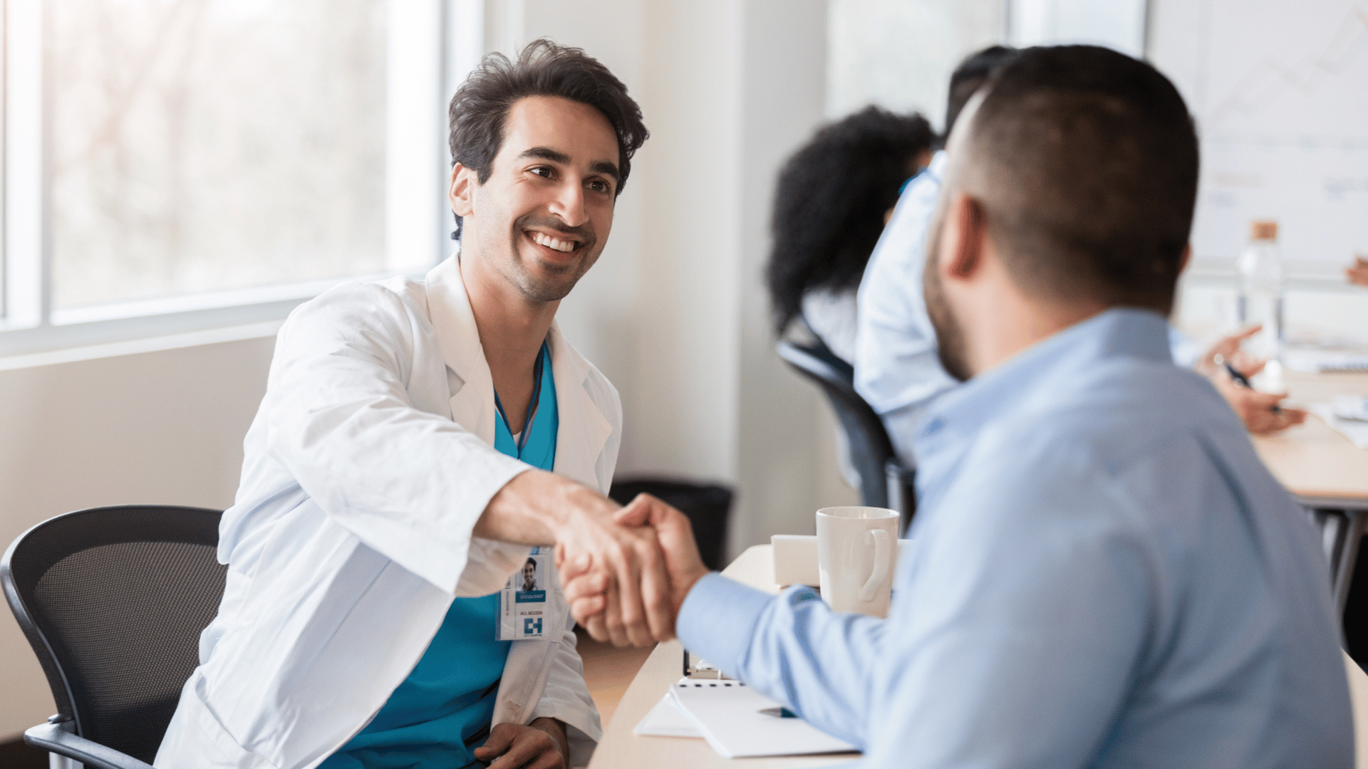 Physician shaking hands with a colleague during a clinical advisory meeting