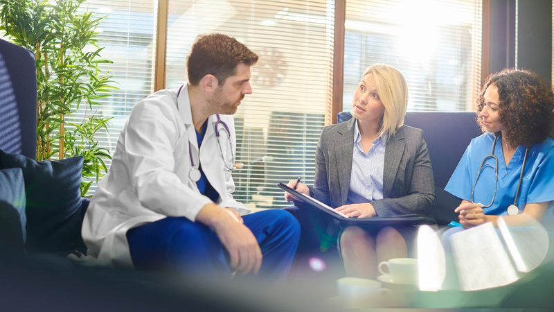 Medical device sales representative reviewing product information with a physician and a nurse