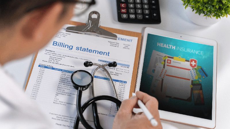Clinician reviewing a billing statement alongside health insurance coverage details